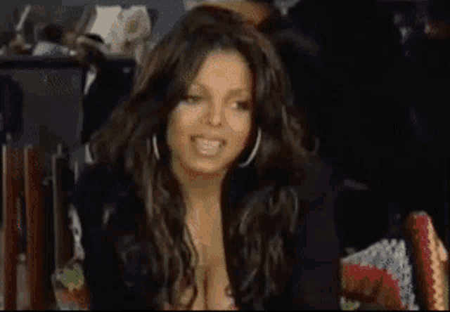 a woman in a black jacket and hoop earrings looks at the camera