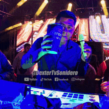 a man in a blue shirt is holding a can of corona