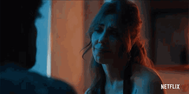 a woman is crying in front of a man with a netflix logo behind her