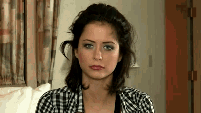 a woman wearing a plaid shirt is sitting on a couch