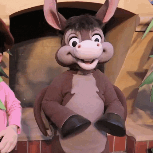 a donkey mascot is standing in front of a fireplace and smiling