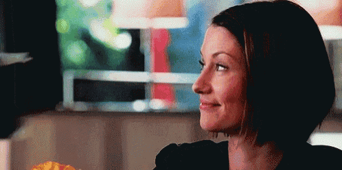a woman with short hair is smiling while looking out a window