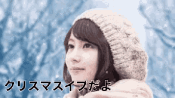 a woman wearing a knitted hat and scarf is looking up at the sky .