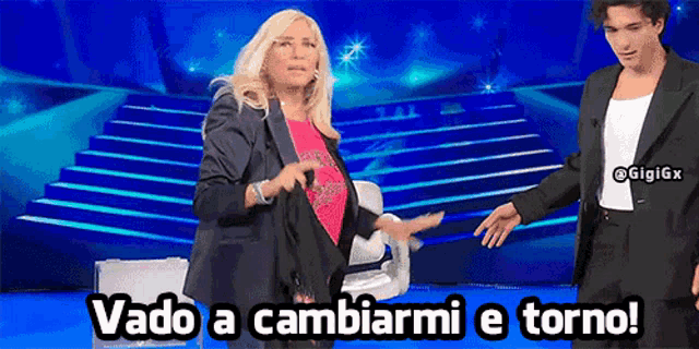 a woman in a black jacket is standing next to a man in a suit and the caption vado a cambiarmi e torno