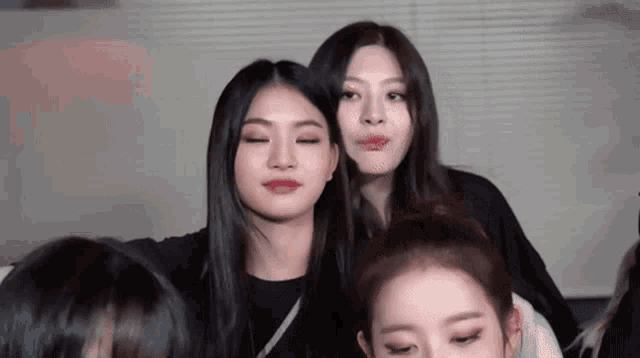 a group of young women are posing for a picture together and one of them is making a funny face .