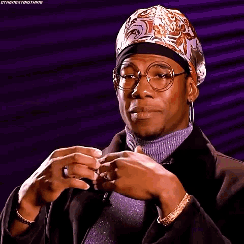 a man wearing glasses and a head scarf is making a face .