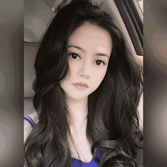 a woman with long dark hair is sitting in a car