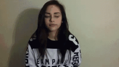 a young woman is making a funny face while wearing a black and white sweatshirt .