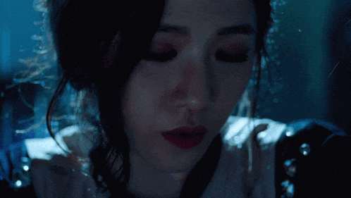 a woman in a dark room with her eyes closed