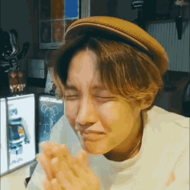 a young man wearing a hat and a white shirt is making a face .