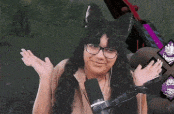 a woman wearing glasses and a cat ear hat is standing in front of a microphone .
