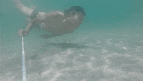 a man is swimming underwater while holding a rope