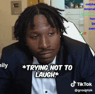 a man in a suit says " trying not to laugh " on a tiktok video