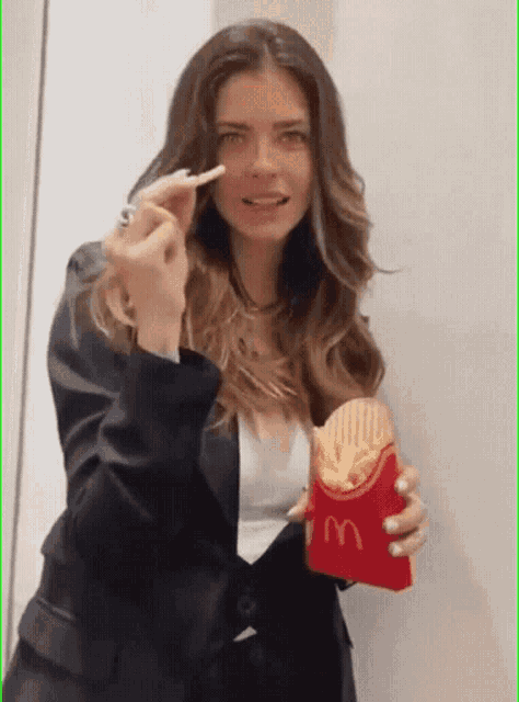 a woman in a suit is holding a mcdonald 's bag of french fries