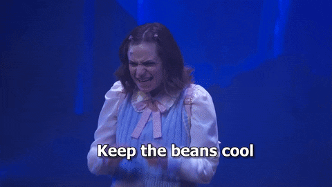 a woman is standing on a stage with the words `` keep the beans cool '' written on the screen .