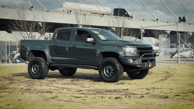 a gray pickup truck is parked in a dirt field