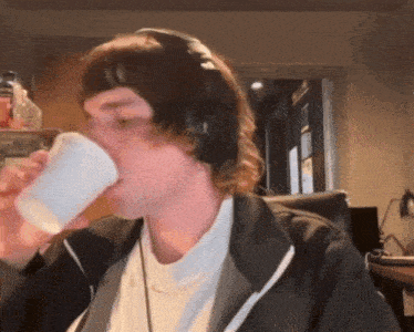 a man wearing headphones drinking from a cup