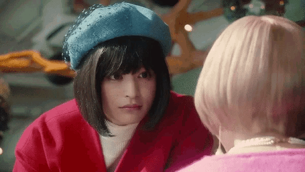a woman wearing a red coat and a blue beret is talking to another woman .
