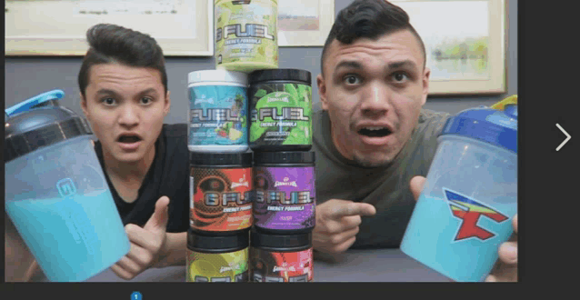 two men are holding up a stack of fuel bottles