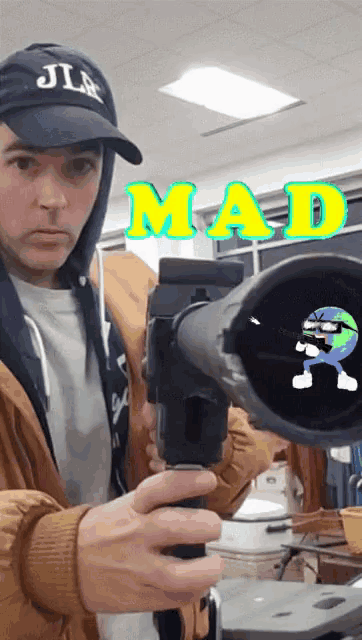a man wearing a hat that says jlm is holding a telescope in front of a sign that says mad