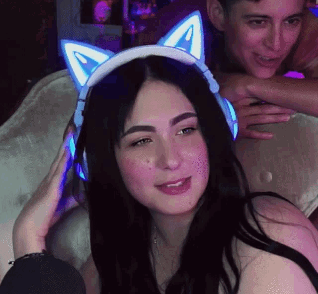 a woman wearing headphones with cat ears on her head looks at the camera