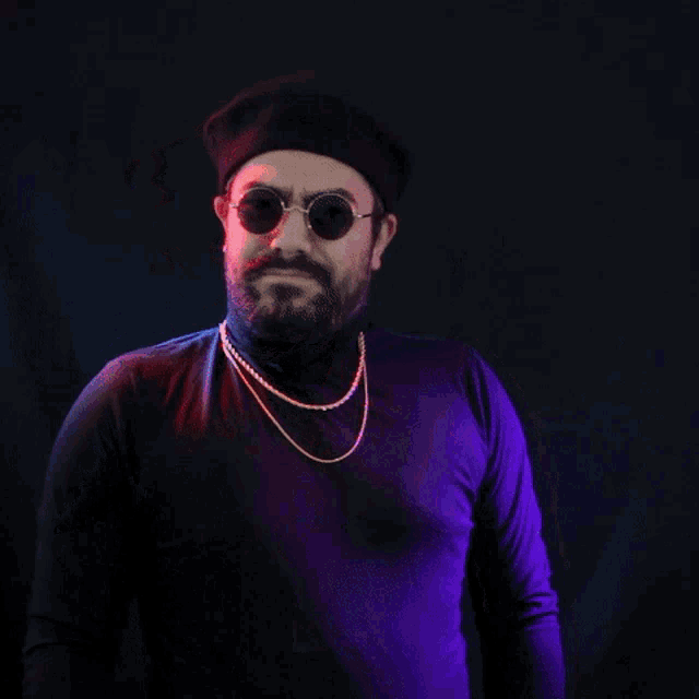 a man with a beard wearing sunglasses and a beret is spraying something with a spray bottle
