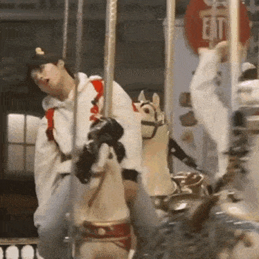 a man is riding a merry go round with a sign that says exit in the background .