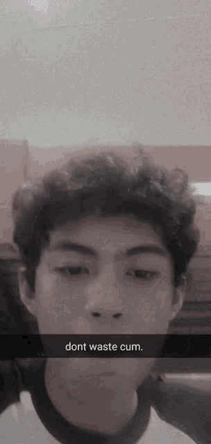 a young man with curly hair is taking a selfie with a caption that says dont waste cum
