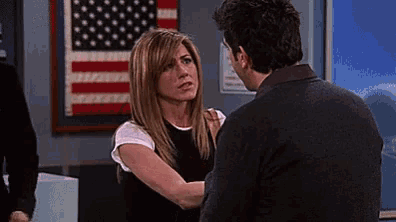 a man and a woman are standing in front of an american flag