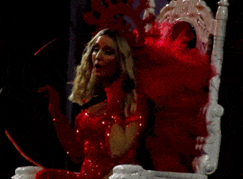 a woman in a red dress is sitting in a chair with a microphone in her hand