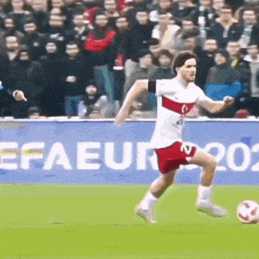 a man in a white shirt and red shorts is kicking a soccer ball
