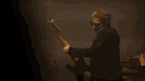 a man in a suit and tie is playing a guitar on stage .