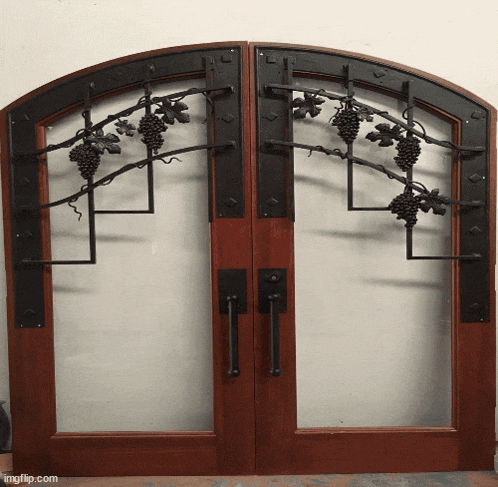 a pair of arched wooden doors with wrought iron grape vines on them
