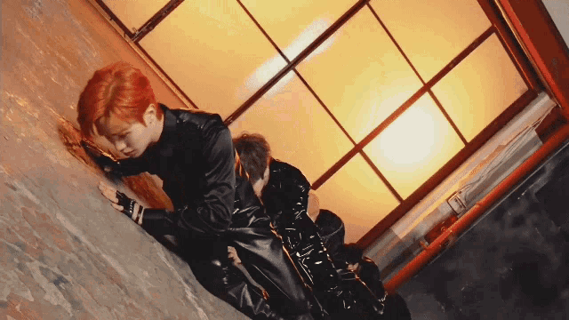 a man in a black leather suit is crawling on the ground