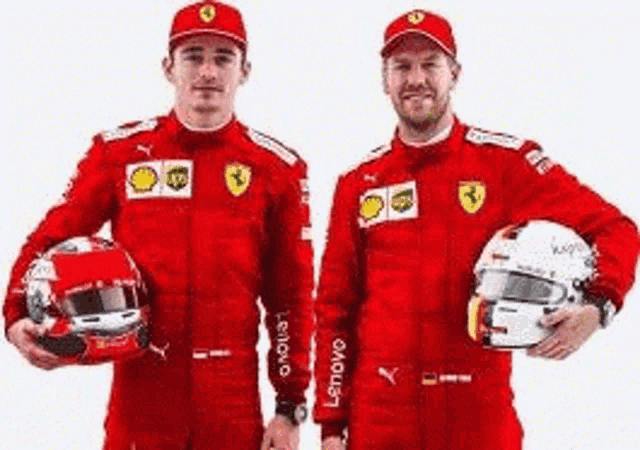 two men in red ferrari suits are holding helmets .