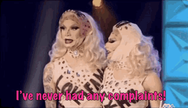 a couple of drag queens are standing next to each other on a stage and talking .