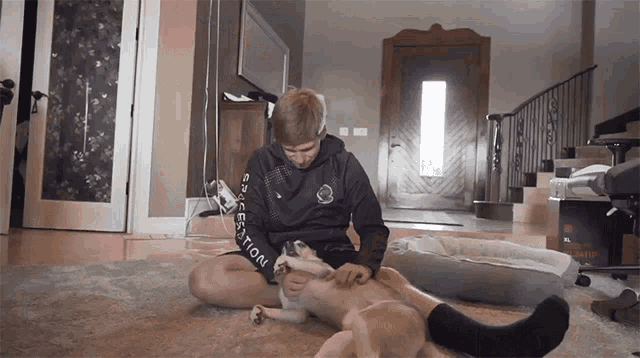 a man is petting a dog while wearing a sweatshirt that says ' sportswear ' on the sleeves