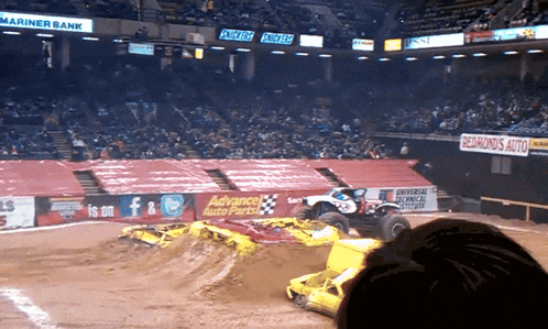 a monster truck is on a dirt track in front of a sign that says advance auto parts