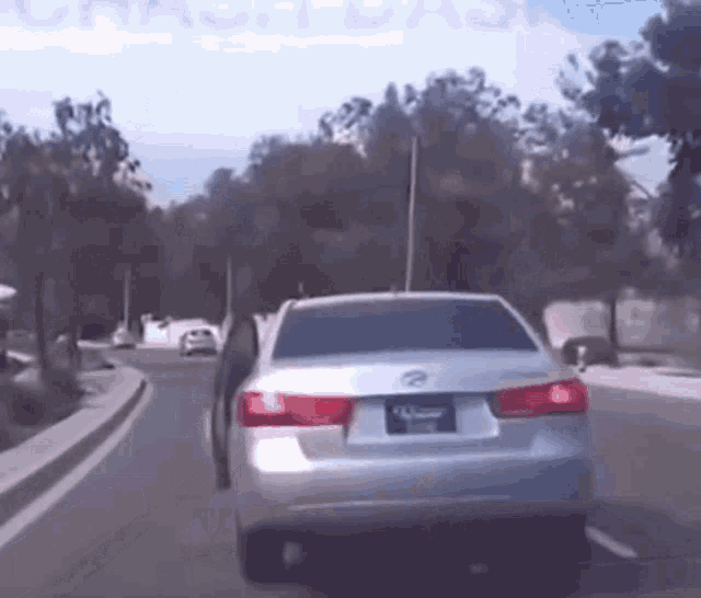 a silver car is driving down a street with a crash dash advertisement in the background