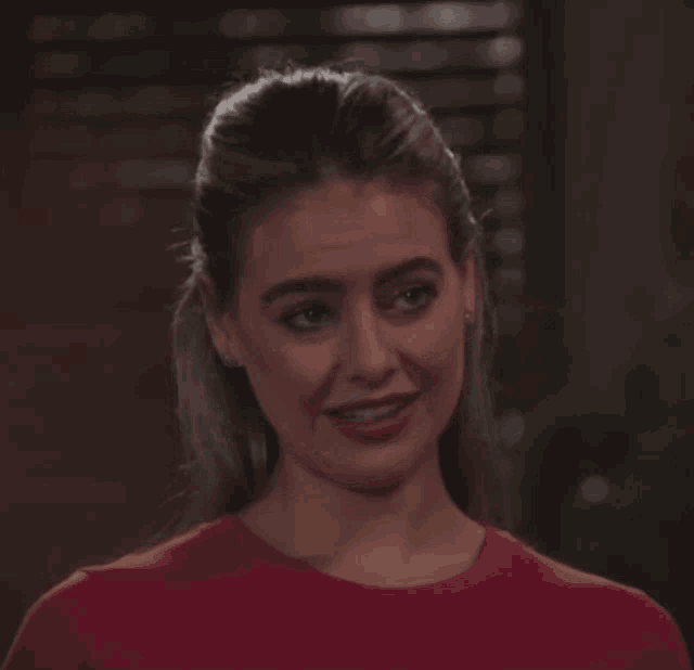 a woman wearing a red shirt is smiling and making a funny face