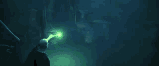 a person is holding a flashlight in a dark room in the dark .