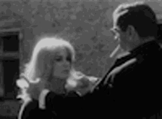 a man is smoking a cigarette while a woman looks on .