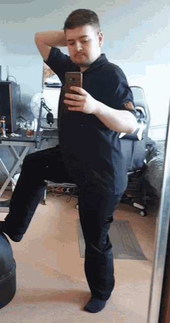 a man in a black shirt is taking a picture of himself in a mirror