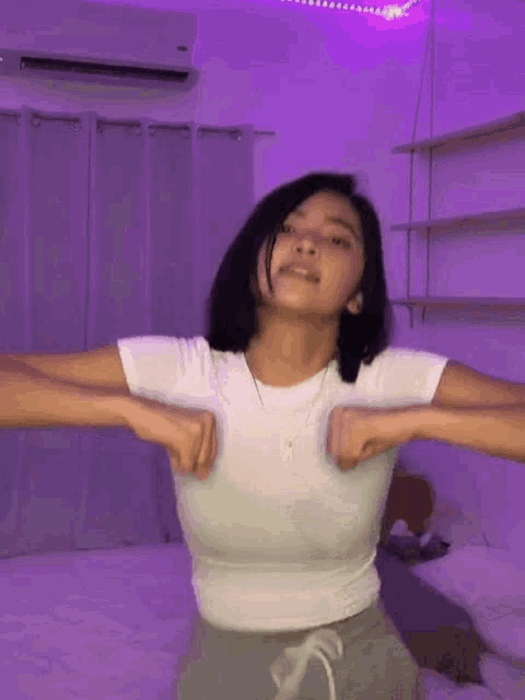 a woman in a white shirt is standing in a room with purple lights .