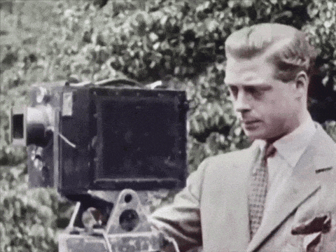 a man in a suit is holding a large camera