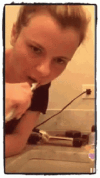 a woman is brushing her teeth in front of a bathroom mirror