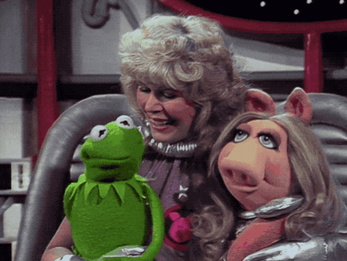 miss piggy and kermit the frog are sitting next to a woman