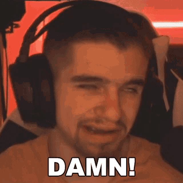 a man wearing headphones is making a funny face and saying damn .