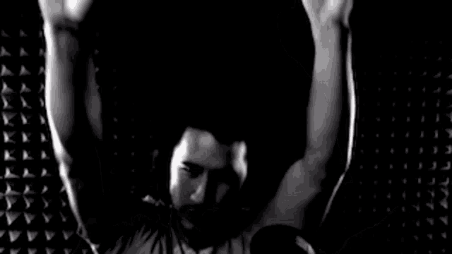 a black and white photo of a man making a devil horns sign with his hands .
