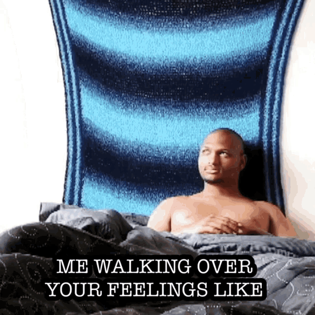 a shirtless man laying in bed with a blue blanket behind him